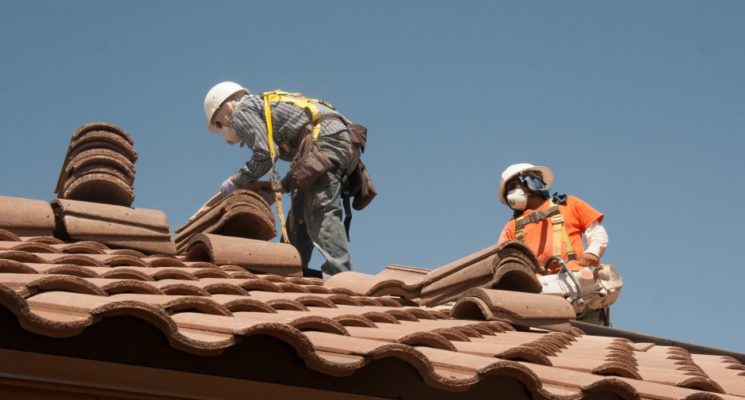 Men installing a curved tiles for roofing